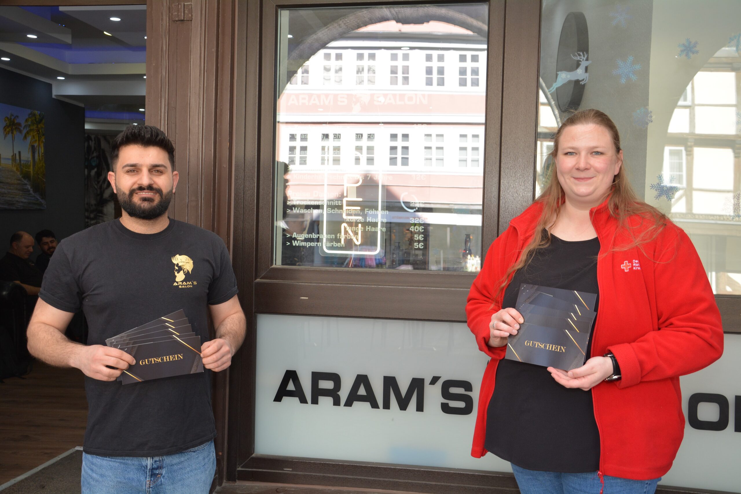 Foto: Friseurmeister Aram Khalid vor seinem Geschäft an den Krambuden. Er überreichte Frederike Schwieger von der DRK-Tafel zehn Gutscheine für Bedürftige. Foto: Regio-Press