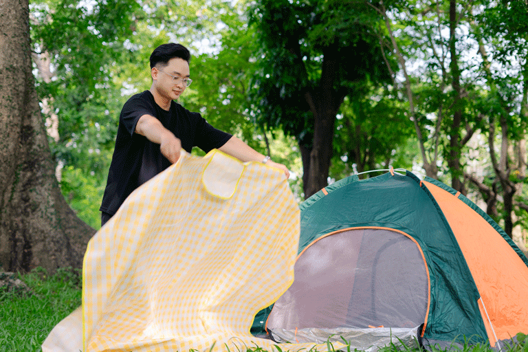 Mann baut ein Zelt auf und breitet eine Decke aus, Landkreis bildet Jugendleiter aus